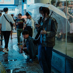 Japanese girl checking her phone under the rain
